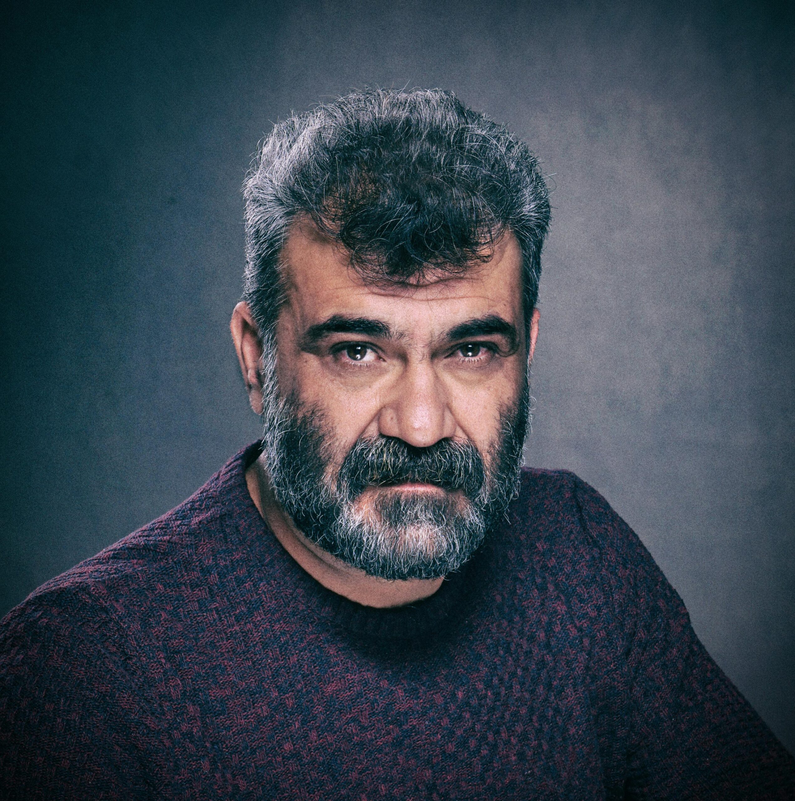 Hombe con barba mirando serio al frente con un jersey