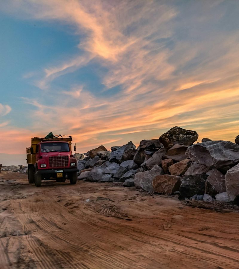 Camión rojo en una carretera de tierra con muchas rocas al lado